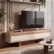 Aura TV Unit in Walnut and Cream styled in a modern living room – Asbar Furniture Yoast Fields Focus keyphrase Aura TV Unit SEO title Aura TV Unit | Walnut & Cream Media Console with Drawers Slug aura-tv-unit Meta description The Aura TV Unit pairs a Walnut-effect top with Cream lacquer drawer fronts, soft rounded corners and a sculptural pedestal base for modern living rooms. Materials Panel الحقل القيمة Leg Material Wood-Effect Hardened Acrylic Frame Material Engineered Wood Primary Material Type Engineered Wood, Wood-Effect Hardened Acrylic, Bronze-Finished Metal Material Finish Cream Lacquer with Walnut-Effect Accents Upholstery / Seat / Back Cushion (فضّيهم) Product short description Aura TV Unit The Aura TV Unit blends sculptural design with modern luxury — a warm walnut-effect top and wrap-around frame paired with smooth cream lacquer drawer fronts, raised on a curved pedestal base. Highlights: Two wide push-to-open drawers Walnut-effect top with wrap-around side panels Smooth cream lacquer drawer fronts Softly rounded corners throughout Sculptural curved pedestal base Coordinates with the Aura living collection Product description Aura TV Unit – Walnut and Cream Media Console with Two Drawers The Aura TV unit brings a refined, sculptural presence to any living room. Designed with a warm walnut-effect top, smooth cream lacquer drawer fronts and a curved pedestal base, the Aura TV unit pairs modern minimalism with a subtle touch of luxury. Design and Finish A walnut-effect surface runs across the top and wraps down the side panels, framing the cabinet in warm tone and fine grain. Cream lacquer covers the drawer fronts below, creating a clean two-tone contrast across the façade. Generously rounded corners soften the entire silhouette, so the piece reads as one continuous form rather than a boxy cabinet. Storage Two wide drawers span the full length of the unit and open with a light push, so no handles interrupt the front. Each drawer offers generous depth for media devices, cables, remotes and everyday living room essentials, keeping the surface above clear and uncluttered. Sculptural Base Curved pedestal legs in a matching walnut-effect finish lift the cabinet clear of the floor. Their overlapping forms create a light, sculptural stance and echo the base design used across the Aura collection. Slim metallic bands wrap the foot of each leg, adding a refined finishing detail. Key Features Two wide push-to-open drawers Walnut-effect top with wrap-around side panels Smooth cream lacquer drawer fronts Softly rounded corners on all edges Sculptural curved pedestal base with metal detailing Generous depth for media equipment and accessories Coordinates with the Aura sideboard and living collection Materials Top and body: Engineered wood with walnut-effect finish Drawer fronts: Engineered wood in cream lacquer finish Legs: Tempered fiber with brushed metal accents The Aura TV unit is part of Asbar Furniture's modern collection — pieces built for UAE homes. Available for delivery and installation across Sharjah, Dubai, and the wider UAE.