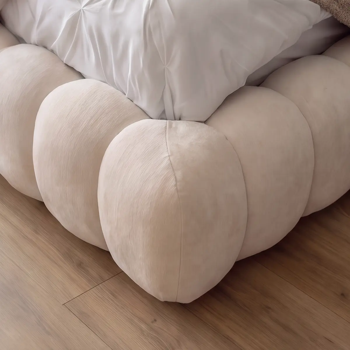Close-up of Recamara Kingbed's rounded bubble-tufted cream upholstered base